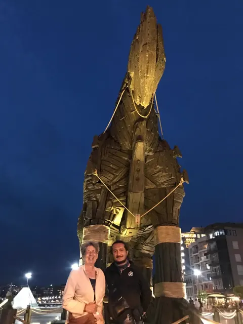 A guide and guest beside the illuminated Trojan Horse on the Çanakkale waterfront.