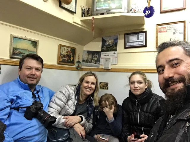 Travellers and their guide gathered for a portrait in a cosy indoor setting.