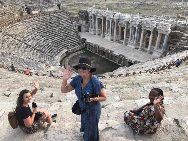 A guide talking with guests beside an ancient theatre.