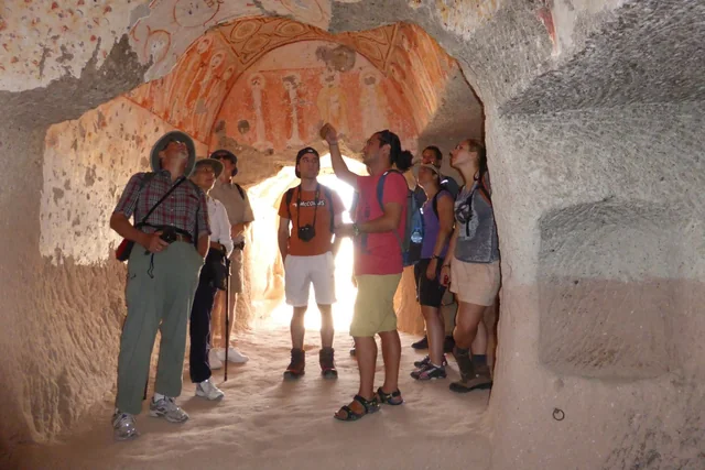 Exploring a rock-cut church A guide speaking with travellers beneath painted walls inside a rock-cut church.