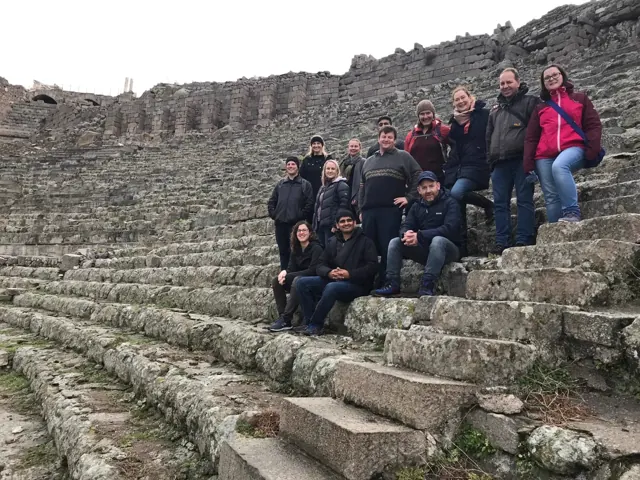 Travellers on the stone seating of an ancient theatre.