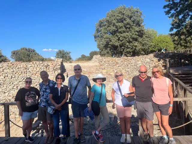 A group pausing together beside ancient stone remains.