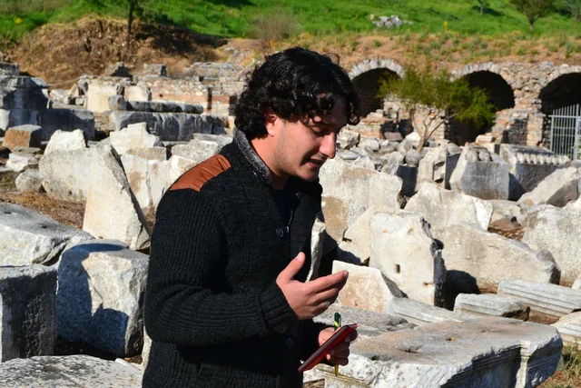A guide speaking beside excavated stone remains at a heritage site.