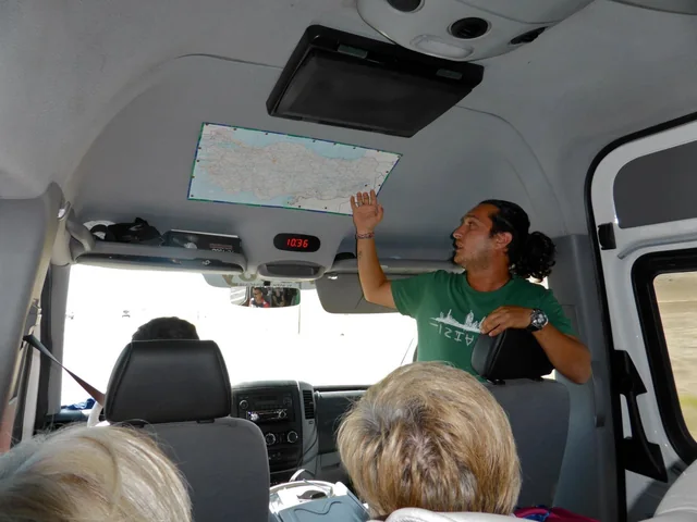 A guide speaking to travellers inside a tour vehicle.
