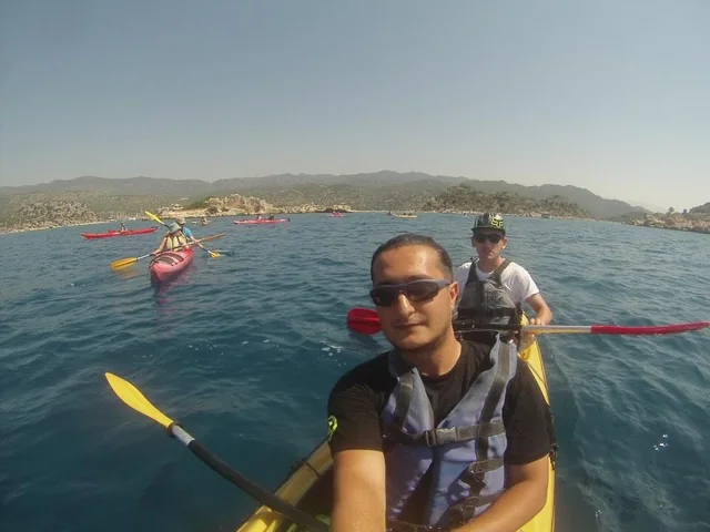 Travellers kayaking across a calm coastal bay.