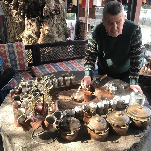 Turkish coffee being prepared on hot sand at a copperware stall.