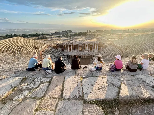 Guests watching sunset beside the monumental statues at Mount Nemrut.