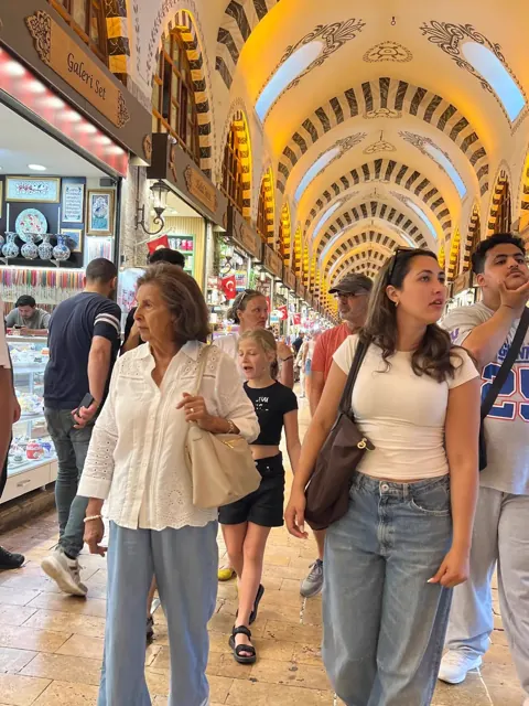 Travellers exploring the decorated vaulted passage of an Istanbul bazaar.