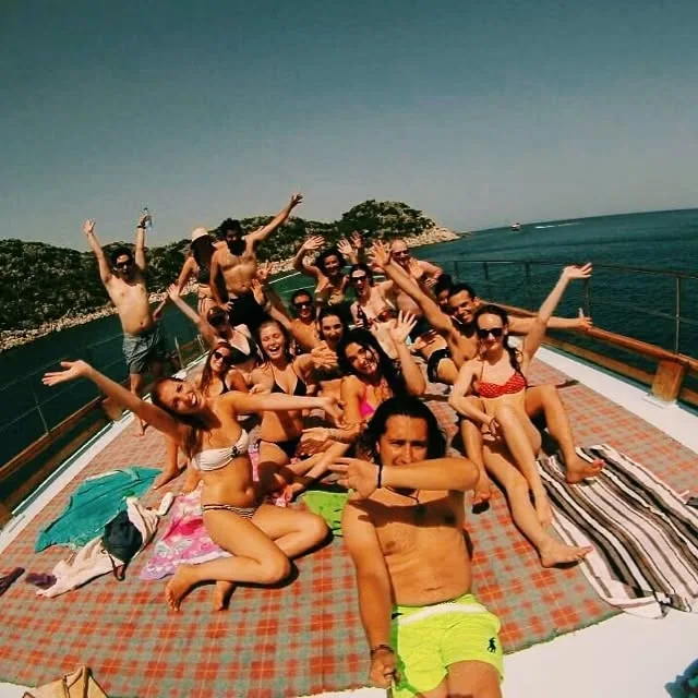 Travellers gathered on the deck of a boat beside the coast.