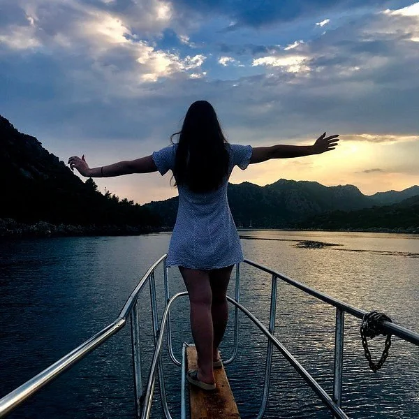 A traveller on a boat overlooking a sheltered bay at sunset.