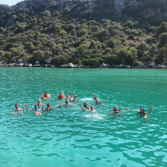 Guests swimming with flotation rings in clear turquoise water.