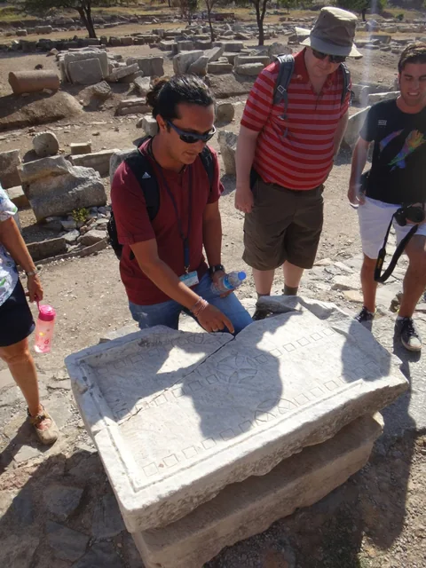 Travellers examining carved stonework among ancient ruins.