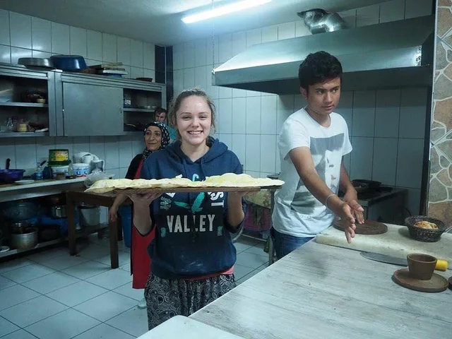 A traveller holding freshly prepared dough in a local kitchen.
