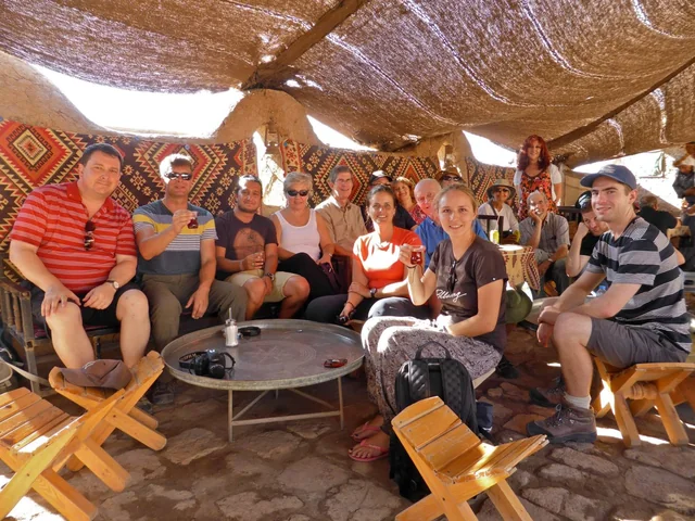 Travellers relaxing together on a shaded terrace with patterned cushions.
