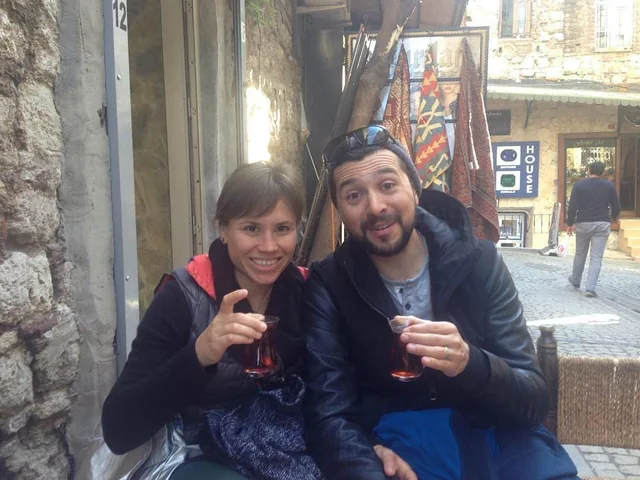 Two travellers enjoying tea beside a stone-lined street.