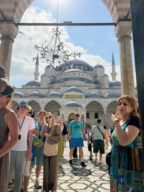 Travellers with their guide beneath an arched mosque courtyard entrance.